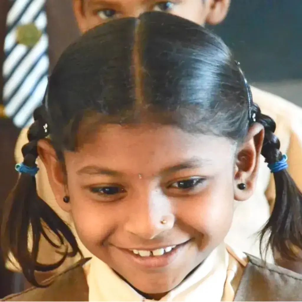 Ein Kind mit zwei Zöpfen lächelt.